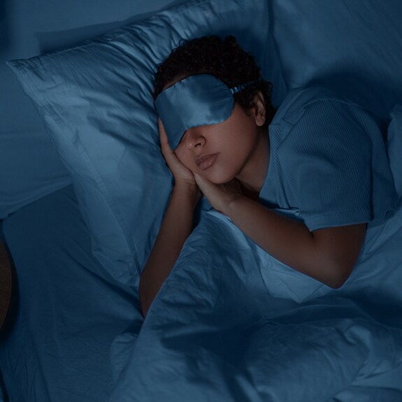 Person sleeping in bed with eye mask