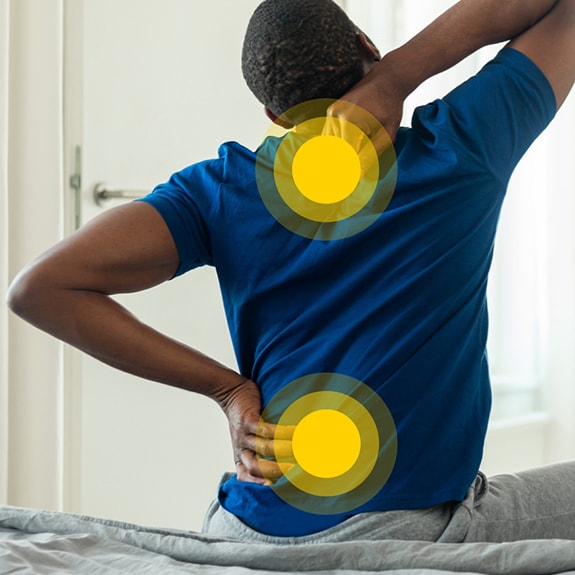 Person with back pain and yellow circles on upper + lower back