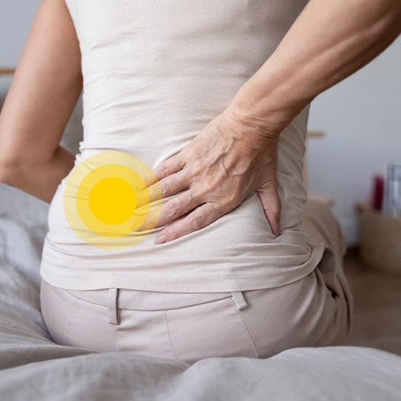 Person with lower back pain and yellow circle on lower back